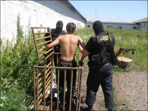 Працівники міліцейського спецпідрозділу ”Сокіл” звільняють з клітки Миколу Гулого. Чоловік не міг сам встати