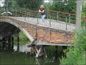 Жителька Козятина Тетяна Чудновець стоїть на аварійному мосту, який веде до міського стадіону. Жінка каже, що асфальт на мосту тріскається просто на очах