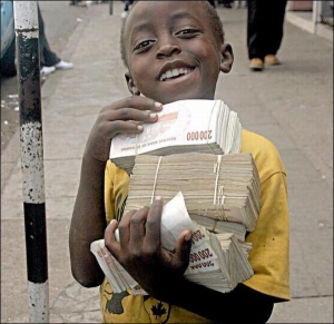 Зимбабвийский мальчик держит кипу местных денег, которые в сумме равны 60 американским центам