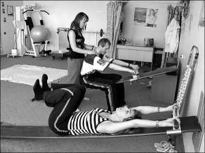 В физкабинете Винницкого госпиталя инвалидов реабилитолог Елена Марняк (на втором плане) выпрямляет спину пациенту на доске Евминова