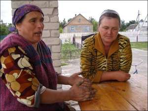48-річна Марія Родзін (ліворуч) з 46-річною односельчанкою Євгенією Олексієвець радяться, як урятувати врожай від кабанів. Жінки сидять на веранді сільського магазину в селі Колки Дубровицького району на Рівненщині