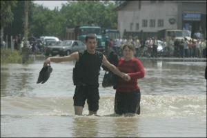Люди переходят затопленную дорогу в Галицком районе Ивано-Франковской области 27 июля 2008 года
