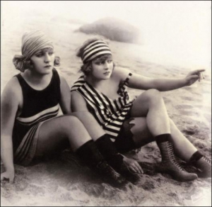 Жінки в купальниках на пляжі, листівка 1920-х років. У той час представниці слабкої статі, як і чоловіки, також почали носити смугасті пляжні костюми. Смужки зазвичай були біла й аквамаринова. Хоч лікарі-гігієністи й далі радили вдягати купальники виключн