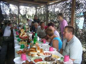 У дворі фермера Леоніда Калакуцького за столом його працівники святкують обжинки. Дружина Калакуцького Наталія (стоїть справа) подає на стіл страви