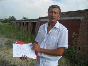 Полтавець Руслан Кисельов біля гаражів по вулиці Вавілова показує рішення суду, яке зобов’язує знести споруди. Чоловік був власником 28 гаражів