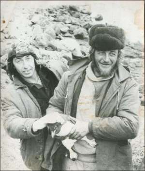 Боцман Євген Махмендаров (праворуч) із матросом Георгієм Колотіліним тримають у руках пінгвіна, який піднявся на корабель по трапу. Знімок зроблений на острові Кергелен