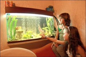 9-річна Віка Хіміч показує сестрі 12-річній Ані нових рибок. Акваріум вмонтований у стіну між кімнатою, коридором та кухнею їхньої квартири у Вінниці