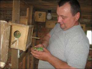 Володимир Трохименко показує різнокольорових папуг у дерев’яному двоповерховому будинку. Цього року чоловік планує добудувати ще один поверх для птахів
