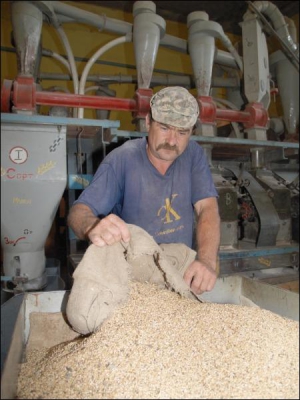 Работник мельницы Александр Дроздюк засыпает зерно в бункер новой электрической мельницы. Мужчина говорит, что после ремонта можно смолоть 100 килограмм зерна за 20 минут. Раньше на это тратили около часа