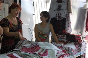 Киянка Катерина Катащинська (ліворуч) вибирає для доччиного весілля рушники, вишиті червоним. Продавчиня Марія Сіреджук пропонує їй вироби із фабричного та домотканого полотна