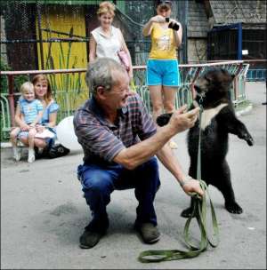 Сотрудник зооуголка Луганского парка культуры и отдыха Василий Сидоренко ведет маленького медвежонка Потапа купаться. 18 августа 2008 года