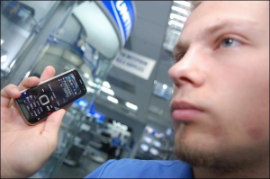 Продавец-консультант столичного магазина ”Юнитрейд”, на площади Независимости, Юрий Стариков включает музыку в телефоне ”Нокия N78”. Благодаря двум наружным  динамикам звучания четкое