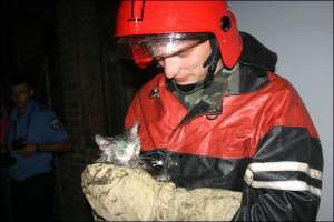 Заступник начальника Октябрського райвідділу МНС Полтави Юрій Колодько тримає врятовану від вогню білу кішку Соню. Від води та кіптяви вона стала брудною