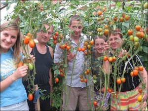 Эмма Саранчук (крайняя справа) с (справа налево) дочкой Олесей, сыном Сергеем, мужем Иваном и невесткой Людмилой в теплице с помидорами. Женщина говорит, что урожай из теплицы лучше, чем с огорода