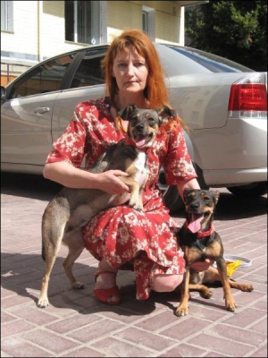 Раиса Анищенко держит на руках псов Тая и Яну. В центре защиты животных Чернигова женщине дали красные ошейники, чтобы защитить ее собак от собаколовов