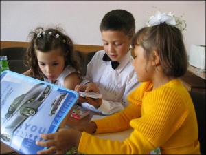 Амир Сердюченко (в центре) рассматривает с 7-летними Аней Карнушак (слева) и Викой Очеретной подарки от мэрии