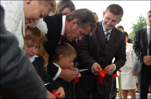 Президент Виктор Ющенко помогает первокласснику перерезать ленту во время открытия новой школы в селе Хотов на Киевщине