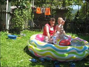 Росіянка Ганна Кочеткова купає сина Олексія та доньку Марію у надувному басейні на подвір’ї своїх батьків у Селі Малий Раковець  Іршавського району на Закарпатті