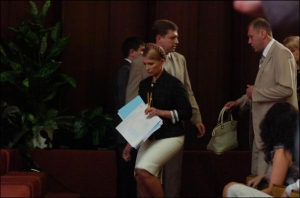 Премьер-министр Юлия Тимошенко поднимается на сцену Украинского дома. Позади один ее охранник передает другому сумочку главы правительства
