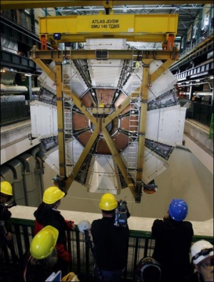 Сотрудники  Европейской организации ядерных исследований наблюдают за тем, как опускают под землю последний элемент аппарата АТЛАС. Он является одним из пяти элементов Большого адронного колайдера