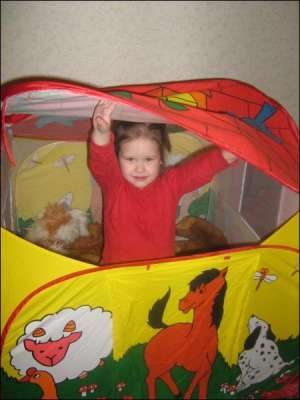 Аня Комар из Полтавы выглядывает из своей игровой палатки. Девочке ее купили полгода назад в гипермаркете ”Метро Кэш энд Кэрри”