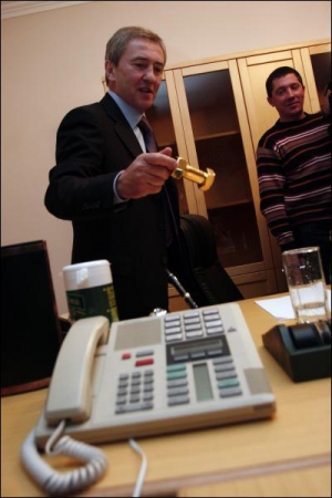 Городской председатель Леонид Черновецкий демонстрирует в кабинете сувенир на рабочем столе — позолоченный болт с гайкой