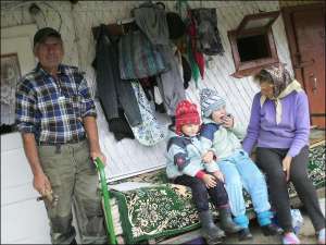 Анастасія (праворуч) і Ірина Мокрянини із села Синевир Міжгірського району Закарпатської області з бабою Василиною та дідом Миколою сидять на ліжку під хатою. Їхня мати виїхала на заробітки до Чехії. Батька дівчатка не мають