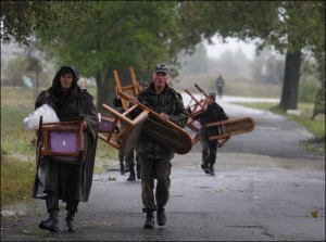 Солдаты несут стулья для чиновников, которые должны наблюдать за военными учениями на полигоне возле села Любомирка, Ривненской области