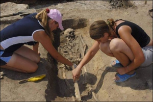 На розкопках церкви в Батурині студентки розчищають кістяки від пилу й піску. Археологічну практику тут проходять українські й зарубіжні студенти. Для багатьох це  нагода добре провести час і поспілкуватися з однолітками