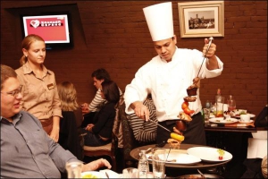 Шеф-повар столичного ресторана ”Нирвана” на бульваре Леси Украинка выносит в зал блюдо ”Меч Тандуры”. На меч нанизаны четыре вида мяса по 200 граммов и стручки болгарского перца
