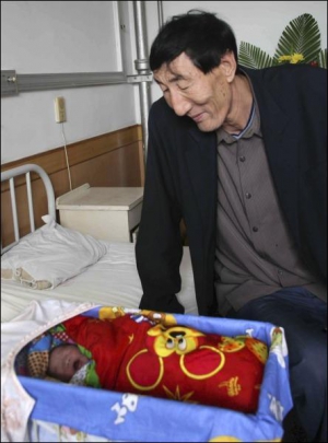 Самый высокий мужчина мира китаец Бао Сишунь возле колыбели новорожденного сына. Нынешнюю жену Сия Шуцзюань мужчина нашел через сайт знакомств. Она родила мальчика весом 4,2 килограмма и ростом 52 сантиметра
