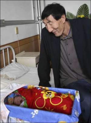Самый высокий мужчина мира китаец Бао Сишунь возле колыбели новорожденного сына. Нынешнюю жену Сия Шуцзюань мужчина нашел через сайт знакомств. Она родила мальчика весом 4,2 килограмма и ростом 52 сантиметра