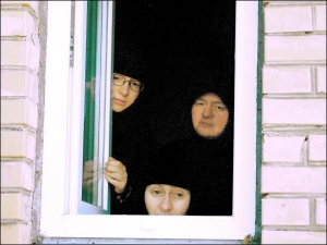Монахини Георгиевской обители на Уманщине выглядывают из окна второго этажа. К себе в монастырь они никого не пускают