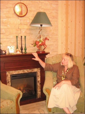 Черкащанка Людмила Папуша сидить  біля  електрокаміну в своїй квартирі. Пристрій імітує вогонь дров. Звукового супроводу не має. Коштує 3,5 тисячі гривень