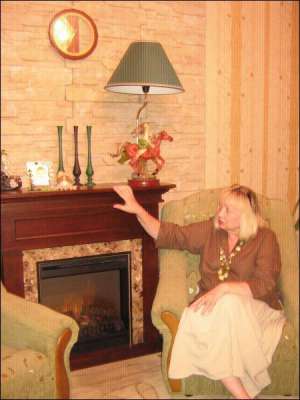 Черкащанка Людмила Папуша сидит около электрокамина в своей квартире. Устройство имитирует огонь дров. Звукового сопровождения нет. Стоит 3,5 тысяч гривен