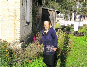Варвара Гінько біля своєї хати в селищі Брюховичі поблизу Львова. За її спиною видно будівлю Василіянського інституту