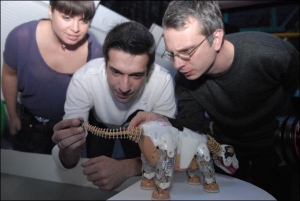 Телеведущий Макс Нелипа (в центре) рассматривает игрушечного динозавра. Слева стоит жена Тамара