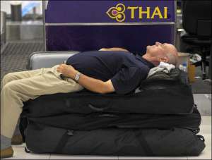 Турист отдыхает на чемоданах в международном аэропорту тайской столицы Бангкок
