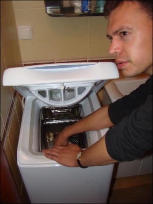 Александр Самийленко закладывает белье и полотенца в стиралку ”Аристон”. Стирку заказал его однокурсник