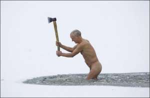 Член минского клуба здорового образа жизни ”Оптималист” разбивает лед на реке Важинке перед новогодним заплывом