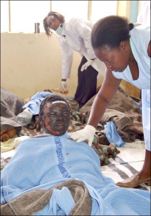 Медсестра осматривает пострадавшего от взрыва бензовоза кенийца
