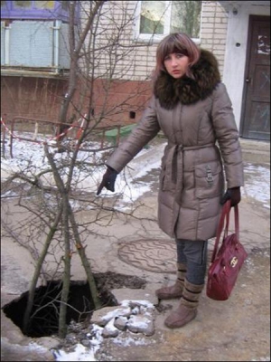 Мария Фищук показывает яму, образовавшуюся после сдвига почвы у подъезда дома на улице Суворова в Монастирище. Специалисты говорят, что земля проваливается в подземные ходы, выкопанные в XVII веке