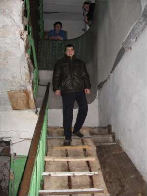 Артем Билявский спускается со второго этажа по самодельной лестнице в доме на улице Советской в Умани. Сверху за ним наблюдают соседки
