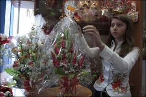 В столичном торговом центре ”Городок” продавец Мария Тихолас снимает ценник с букета, сделанного из искусственных цветов и конфет. Его купили на подарок. Самый дешевый ”сладкий” букет стоит 65 гривен