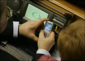 Симоненко показывает фотографию своей дочери на мобильном телефоне в зале заседаний Рады. 17 марта.