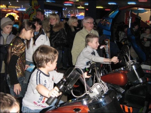 На відкритті черкаського торгово-розважального центру ”Пластилін” діти катаються на симуляторі мотоцикла ”Харлі Девідсон”. Вартість однієї ”поїздки” — від 6 гривень