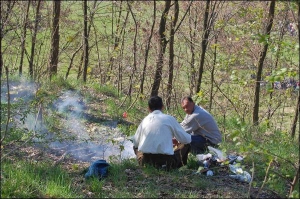Отдыхающие жарят сардельки на костре в воскресенье после обеда в парке ”Вознесение” во Львове. Мусор складывают рядом за спиной