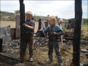 Владимир Бондарь (справа) с сестрой Марией и родным дядей Дмитрием Дошуко, 9 лет, разбирают сгоревший сарай