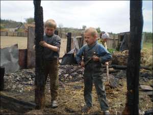 Володимир Бондар (праворуч) із сестрою Марією та рідним дядьком Дмитром Дошуком, 9 років, розбирають згорілий сарай