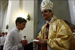 Архієпископ Никола Етерович причащає киянина Семена Гуртовенка у римо-католицькому соборі святого Олександра в неділю, 24 травня 2009 року
